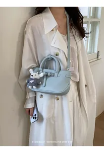 Close-up of a stylish light blue leather handbag with a cute bunny charm accessory.