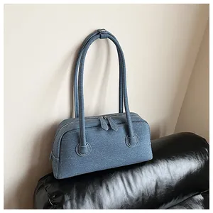 Detailed view of a stylish blue denim texture Boston bag on a black leather surface.