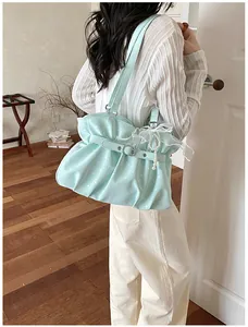 Side view of mint green polka dot pleated tote bag with bow detail on model shoulder