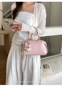 Chic pink Boston handbag with cute charm shown in a minimalist retro lifestyle setting.