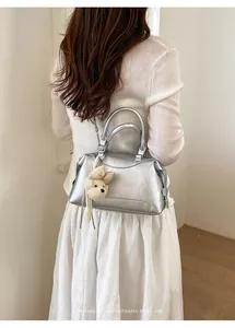 Detailed back view of a silver Boston handbag with a cute bear charm on a model.