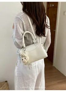Detailed view of white Boston bag on model showcasing crossbody style and dog charm