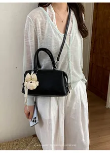 Detailed view of the black Boston handbag featuring a cute plush puppy charm accessory