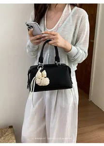 Stylish woman holding a black Boston handbag with a cute plush dog charm detail