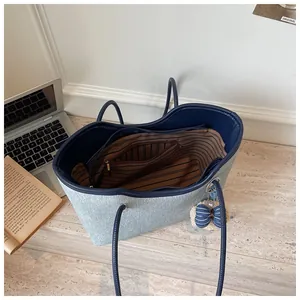 Detailansicht einer großen Denim-Tasche mit gestreiftem Futter und Schleifenanhänger.