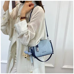 Light blue denim shoulder bag with navy blue trim and plush puppy charm detail