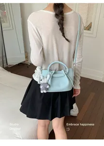 Back view detail of a light blue leather bucket bag with a cute white rabbit charm