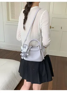 Back view of a woman wearing a lavender leather bucket bag with a plush dog charm