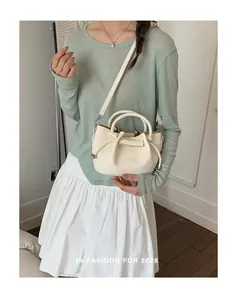 Close-up of elegant cream white bucket bag with handles worn by a female model.