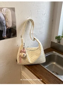 Trendy cream white polka dot shoulder bag featuring a cute poodle charm in a cafe setting