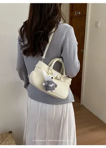 Back view of a model carrying a cream textured leather bag with a cute rabbit charm