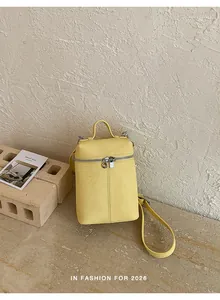 Detailed close-up view of a minimalist yellow mini bucket bag with crossbody strap