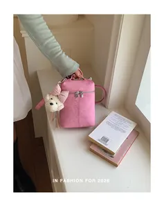 Detail view of pink textured mini bucket phone bag with a cute plush bear charm