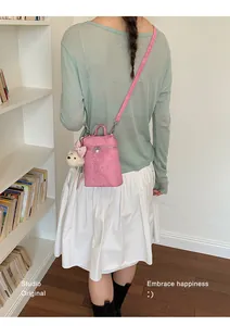 Back view of a trendy pink mini bucket crossbody bag with a plush bear accessory