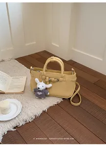 Sophisticated yellow leather handbag with top handles and a cute bunny charm