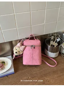 Close-up detail of a pink mini crossbody bucket bag featuring a cute white dog plush pendant.