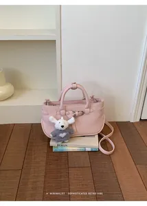 Pink minimalist handbag on wooden floor with cute white plush dog keychain detail