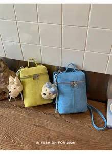 Two minimalist suede crossbody bags in yellow and blue with cute teddy bear charms.
