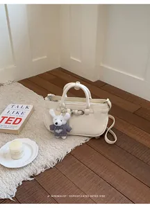 Detail view of a cream pebbled leather bag in a minimalist indoor setting with retro vibe