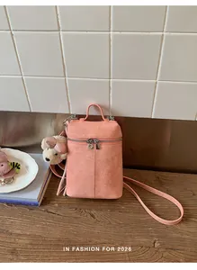 Detail of pink suede-textured mini bucket bag featuring a cute teddy bear charm