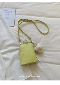 Close-up of a minimalist lime green crossbody mobile phone bag with a cute bear charm.