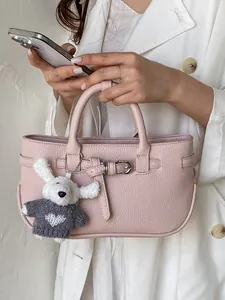 Elegant pink textured leather handbag with plush rabbit charm and buckle detail.