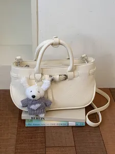 Elegant cream white textured leather handbag for women featuring a cute rabbit charm