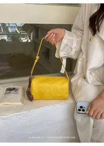 Minimalist yellow pillow bag styled with a white outfit and strawberry charm detail.