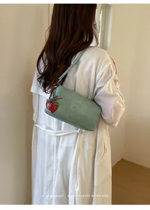 Close-up of a light blue pillow bag worn by a model featuring a strawberry charm