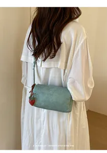 Detailed view of a minimalist light blue pillow bag featuring a cute strawberry charm