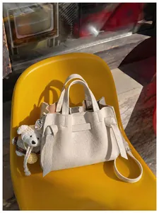 Sac à main raffiné en cuir texturé blanc cassé avec détail de nœud sur une chaise jaune