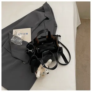 Vue détaillée du sac fourre-tout en cuir grainé noir avec pochette et charme chien.