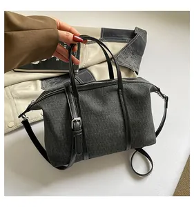 Detail view of a dark grey canvas tote bag with black leather straps and handles.