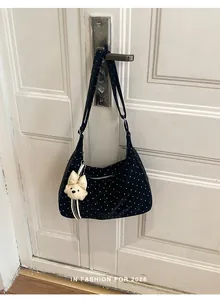 Stylish black polka dot shoulder bag hanging on a white door with cute puppy charm
