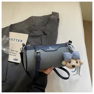 Detail showing elegant blue and grey canvas cylinder bag with a cute teddy bear charm