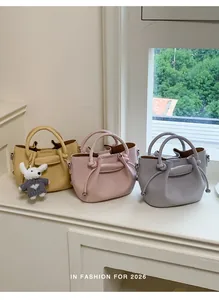 Three colors of elegant women's bucket handbags displayed by the window.
