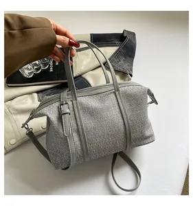 Close-up of a grey canvas handbag with leather straps held in a lifestyle setting
