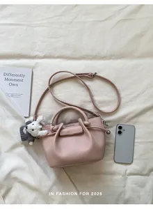 Top down flat lay view of a pink pebbled leather bucket bag with a cute puppy charm