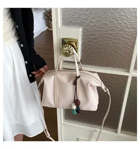 Detail shot of a cream canvas commuter bag hanging on a door handle with colorful beads.