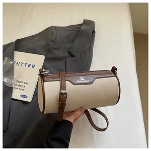Close-up of a stylish cream canvas and brown leather cylindrical crossbody bag for women