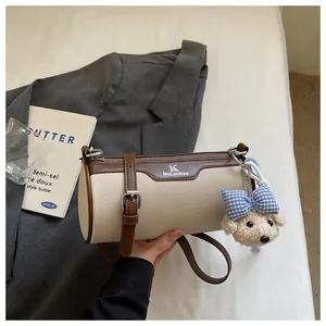 Macro view of beige canvas barrel bag with brown leather trim and cute dog charm