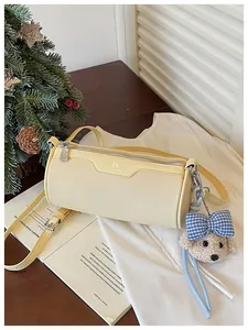 Detailed view of cream cylindrical crossbody bag with cute teddy bear plush charm and bow