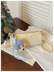 Close-up of a yellow barrel crossbody bag with MuLanKou logo and a cute teddy bear charm.