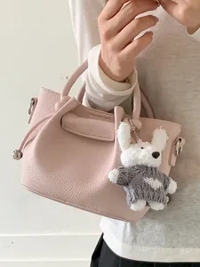Elegant pink textured leather bucket handbag featuring a cute plush rabbit keychain for women