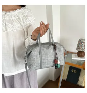 Close-up of a grey textured canvas tote bag with a colorful decorative bead charm
