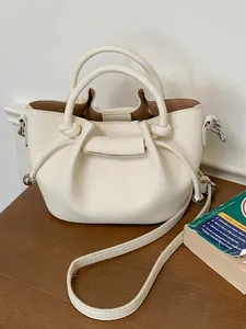 Elegant white pebbled leather bucket bag with knotted drawstring and crossbody strap for women.