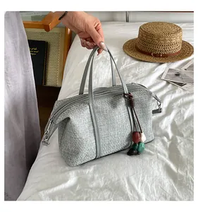 Detail view of casual gray canvas tote bag with leather handles and colorful bead tassel