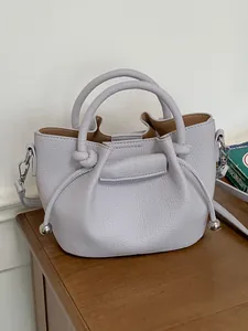 Light purple textured leather bucket handbag with top handles and crossbody strap