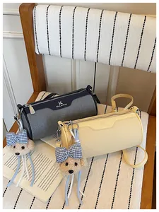 Detail view of two stylish cylinder crossbody bags featuring cute teddy bear charms