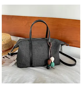 Close-up of casual dark gray canvas tote bag with colorful bead charm on a wooden background.